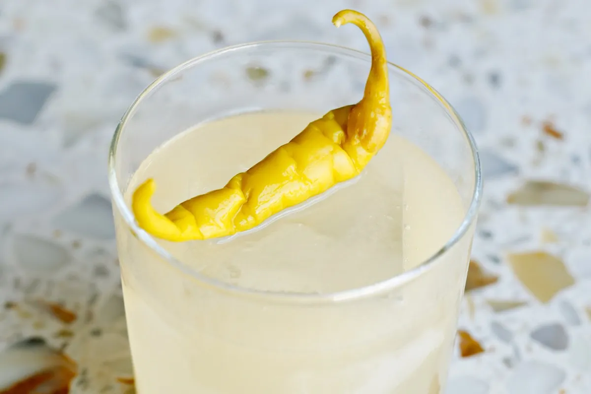 A cocktail garnished with a pickled pepper
